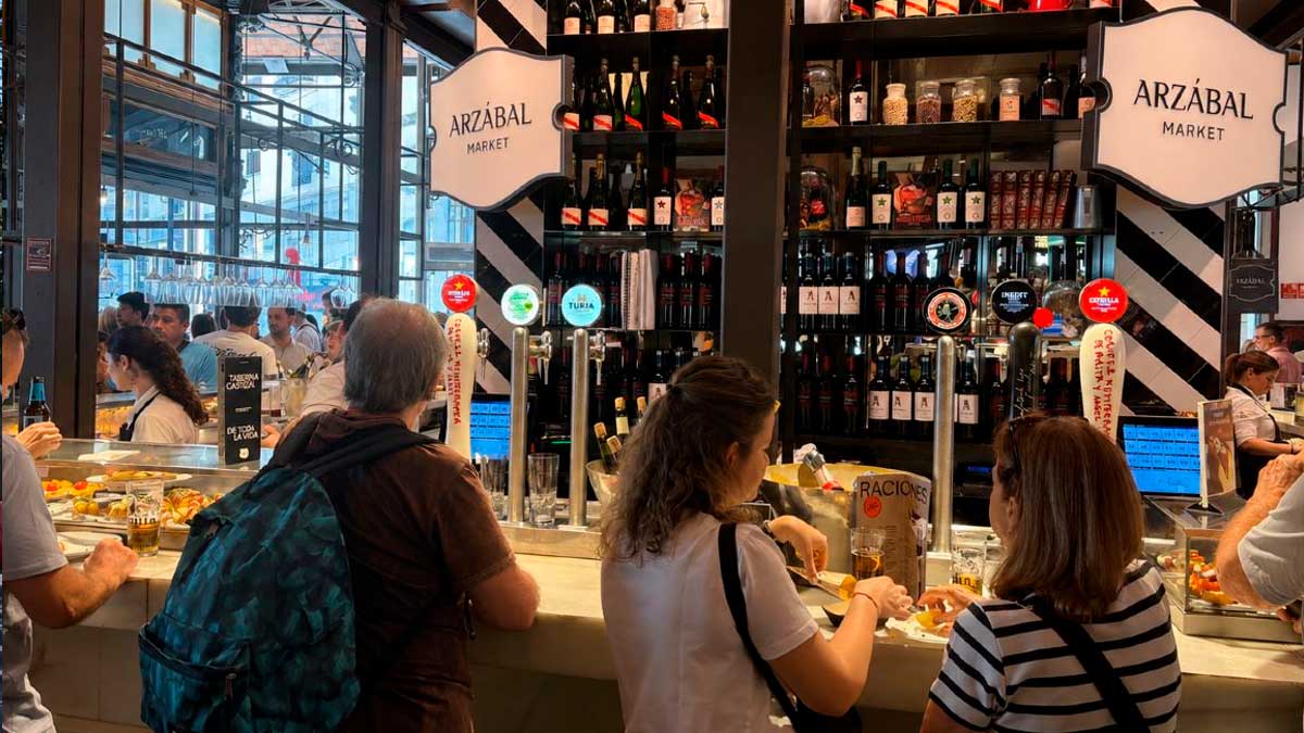 Interior del Mercado de San Miguel con visitantes recorriendo sus puestos gastronómicos.