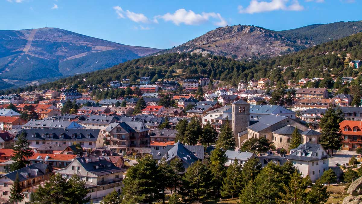 Vista panorámica de Navacerrada en verano con casas y montañas al fondo, población cerca de 10.000 habitantes