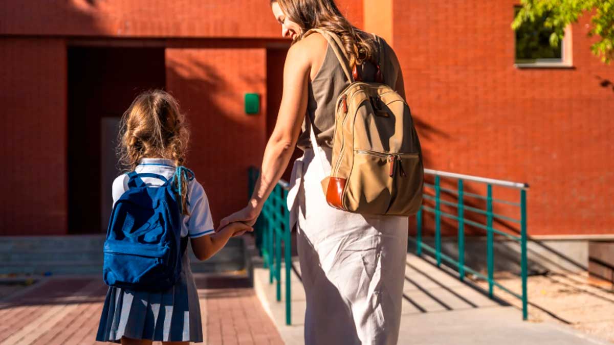 Una madre acompaña a su hija entrando a un colegio de Madrid al inicio del curso 2026-27.